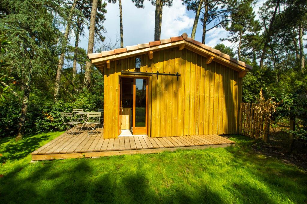 a wooden cabin with a deck in the grass at Cabane forêt proche plage in Pyla-sur-Mer