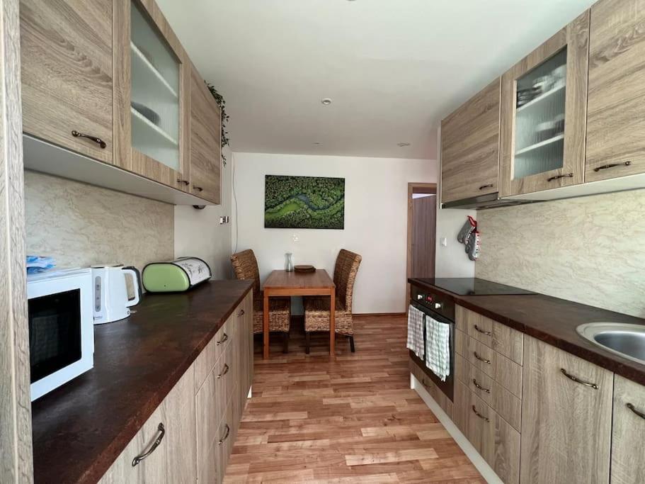 a kitchen with wooden cabinets and a table with a microwave at Apartman centrum Šturka in Martin