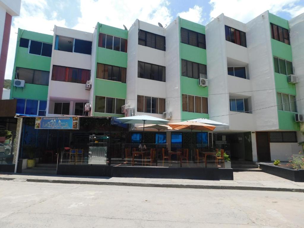 a building with tables and umbrellas in front of it at El Velero Apartamentos By DANP in Santa Marta