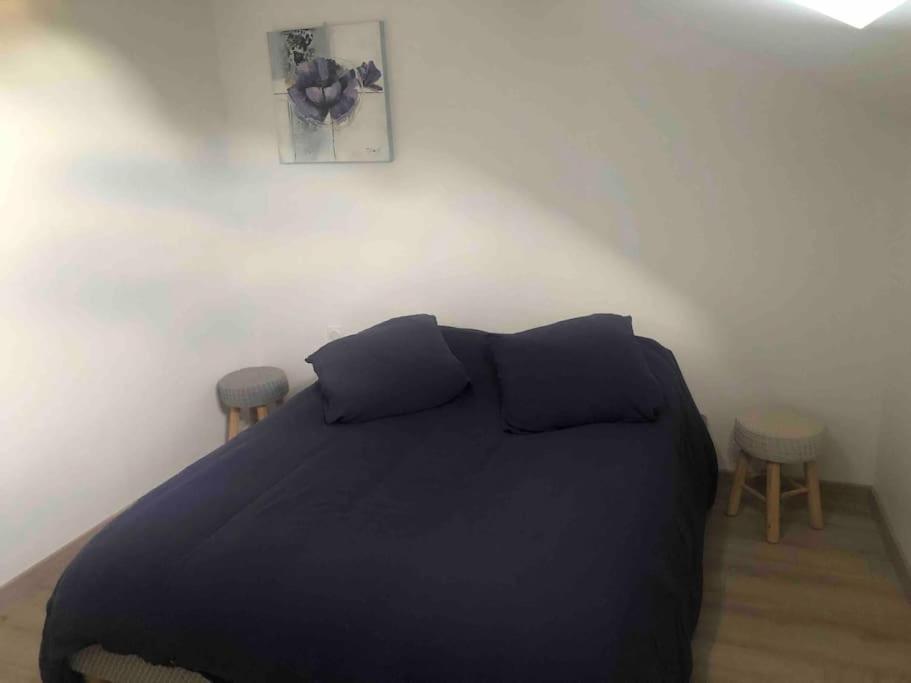 1 dormitorio con 1 cama negra y 2 taburetes en appartement duplex en Beaune-la-Rolande
