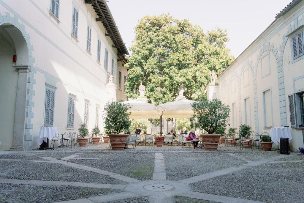 un groupe de personnes assises à une table dans une cour dans l'établissement Caffè delle Rose Les Chambres, à Verbania