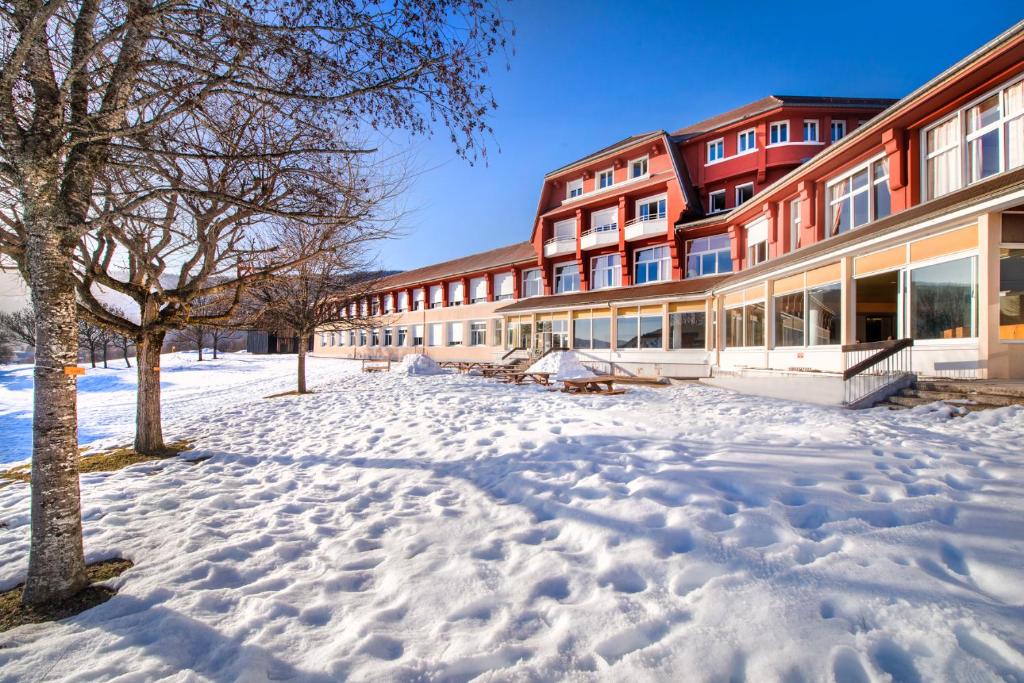 un bâtiment avec de la neige devant lui dans l'établissement L'ESCANDILLE Village Vacances, à Autrans