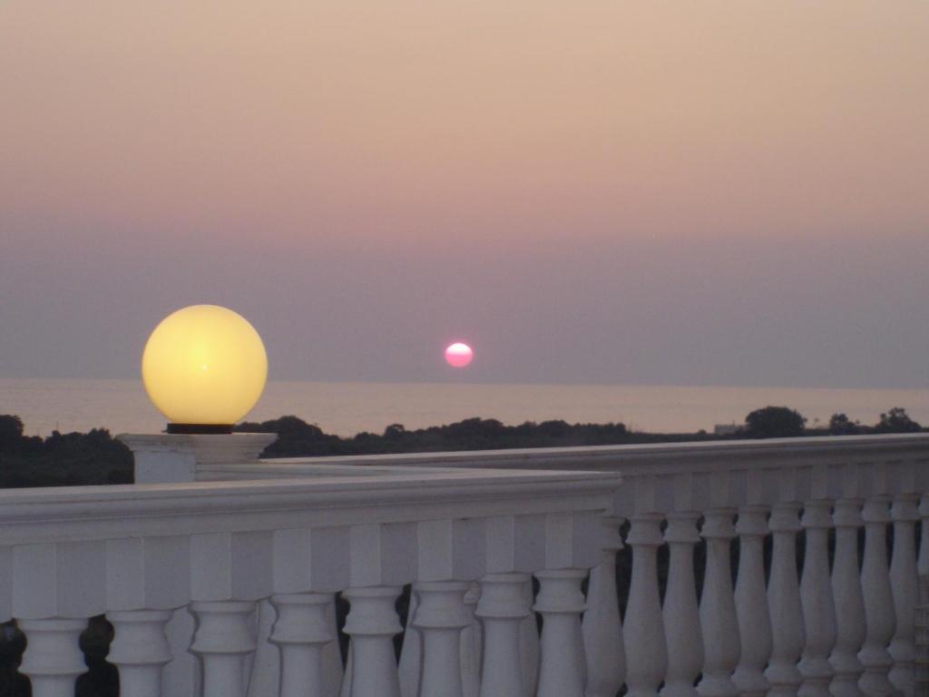 a sunset over the white fence with the sun in the distance at Ionion Star Hotel in Tholón