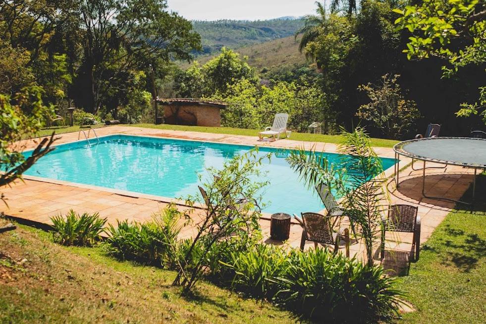 una piscina en un patio con mesa y sillas en Pousada Suçuarana en Itabirito