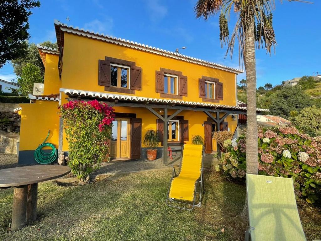 a yellow house with a bench in front of it at CASA DOS FALCÕES casa rural de construção tradicional in Fajã da Ovelha