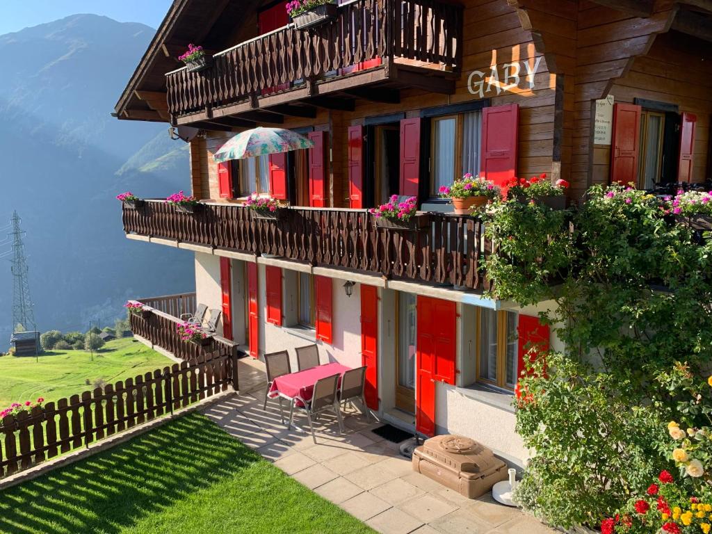 a house with red doors and a balcony with flowers at Gaby in Grächen
