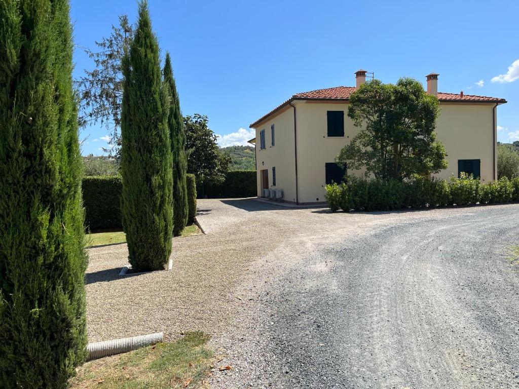 una casa y árboles al lado de una carretera en Holiday House La Rosa, en Terricciola