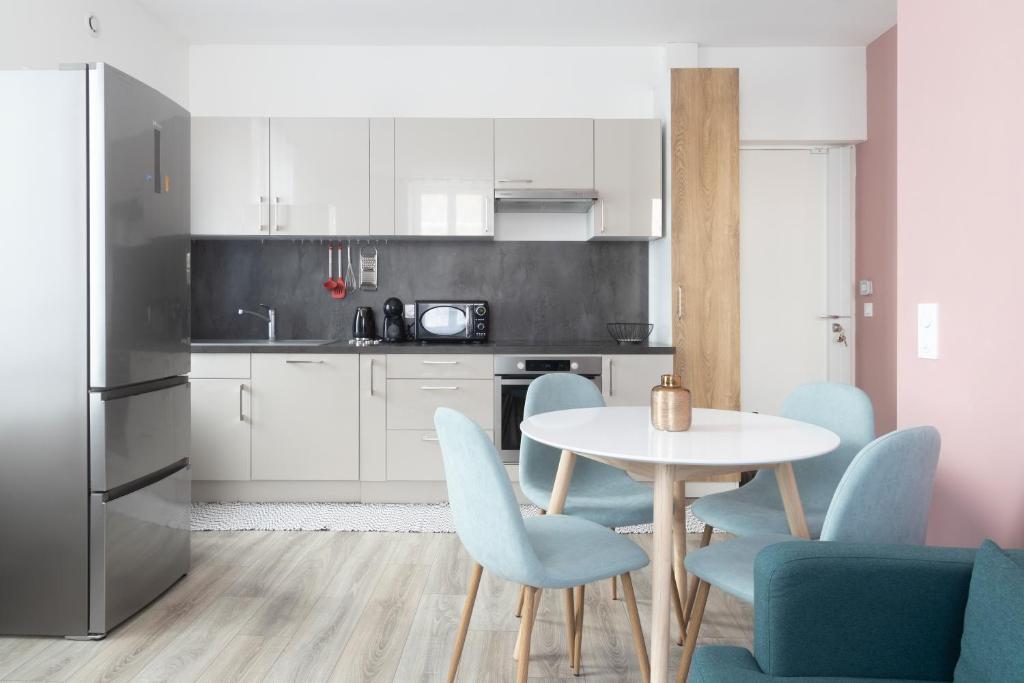 a kitchen with a white table and blue chairs at LIKE CASA- Centre/Gare in Valence