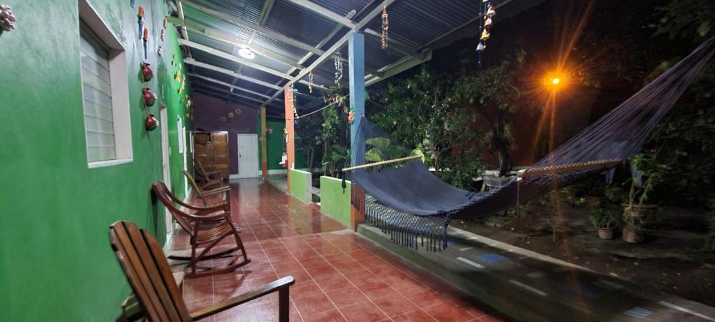 eine Veranda mit einer Hängematte und einem grünen Gebäude in der Unterkunft Hospedaje y Restaurante la cocina de Mami in Moyogalpa