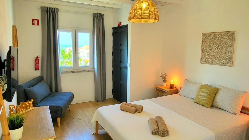 ein Schlafzimmer mit einem großen Bett und einem blauen Sofa in der Unterkunft Cantinho de Milfontes in Vila Nova de Milfontes