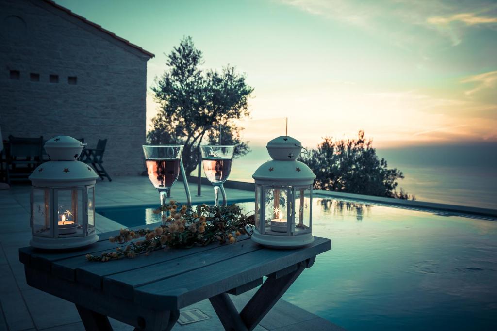 a table with wine glasses and lights next to a swimming pool at TOPAZ AGIOS NIKITAS in Agios Nikitas
