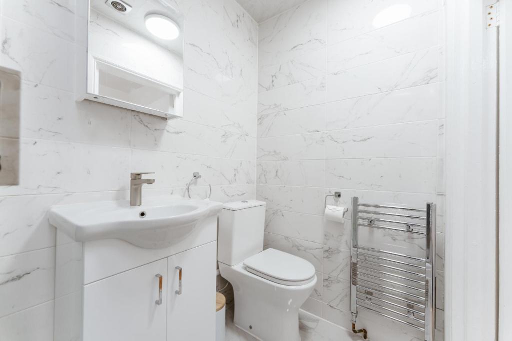 a white bathroom with a toilet and a sink at Notting Hill Guest Flat in Ealing