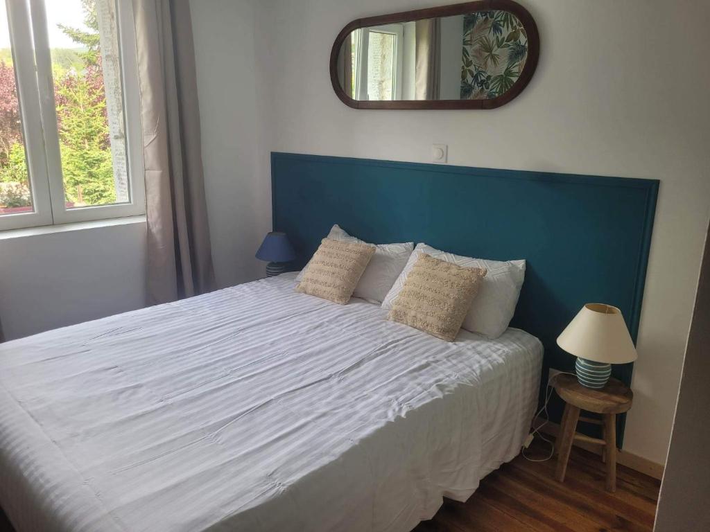 - une chambre avec un lit doté d'une tête de lit bleue et d'un miroir dans l'établissement Petite maison avec jardin privé, au Malzieu-Ville