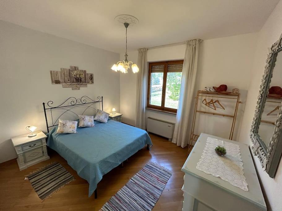 a bedroom with a blue bed and a window at Nido di Rina in Ponte A Bozzone