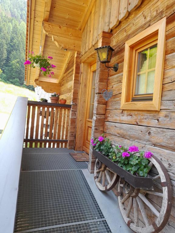 a porch of a wooden house with flowers in a planter at Ferienwohnung Dienerhof in Großkirchheim