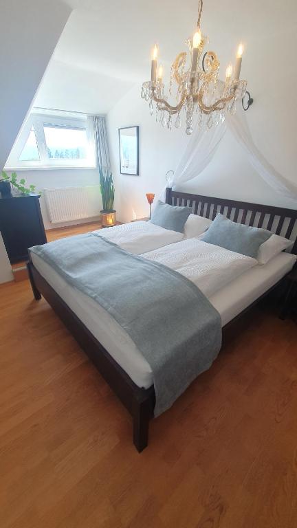 a large bed in a bedroom with a chandelier at Lakeside Hills - Classic Room in Krumpendorf am Wörthersee
