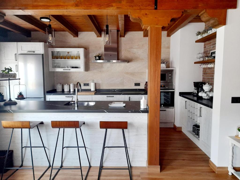 a kitchen with a sink and two bar stools at CASA RURAL EL TRASTERO DE CARMELO in Maello