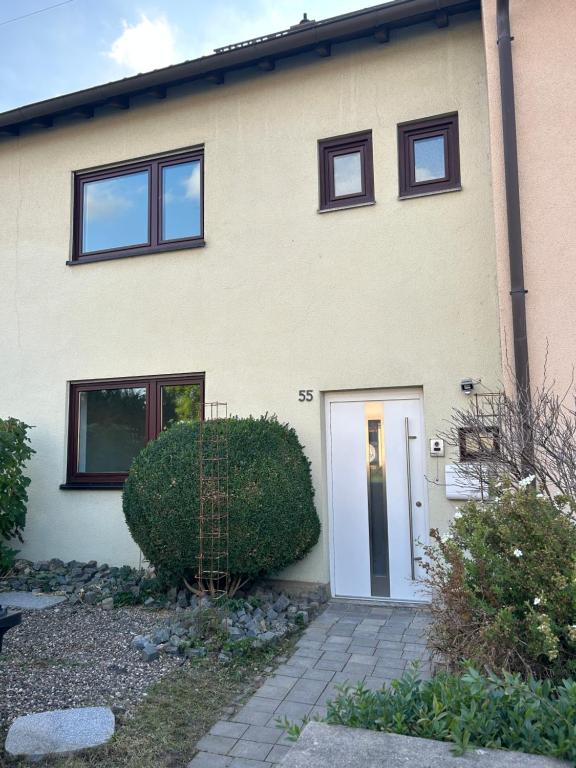 una casa con una porta bianca e un cespuglio di Ferienhaus in Amstetten 