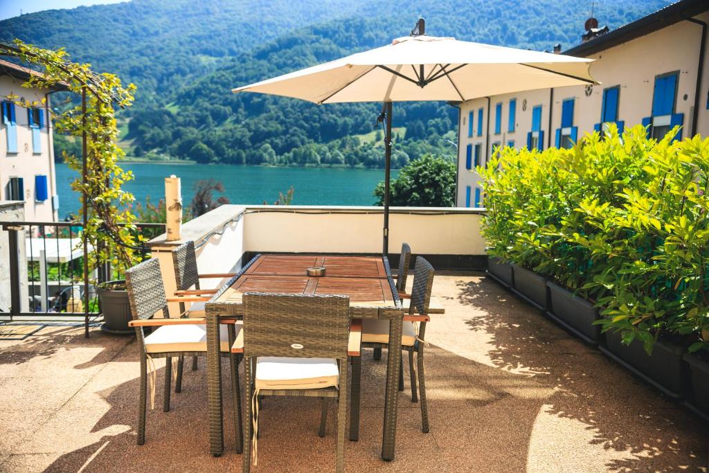 una mesa y sillas con una sombrilla en el balcón en THE SECRET SUITE - HOME "Lago di Endine", en Ranzanico