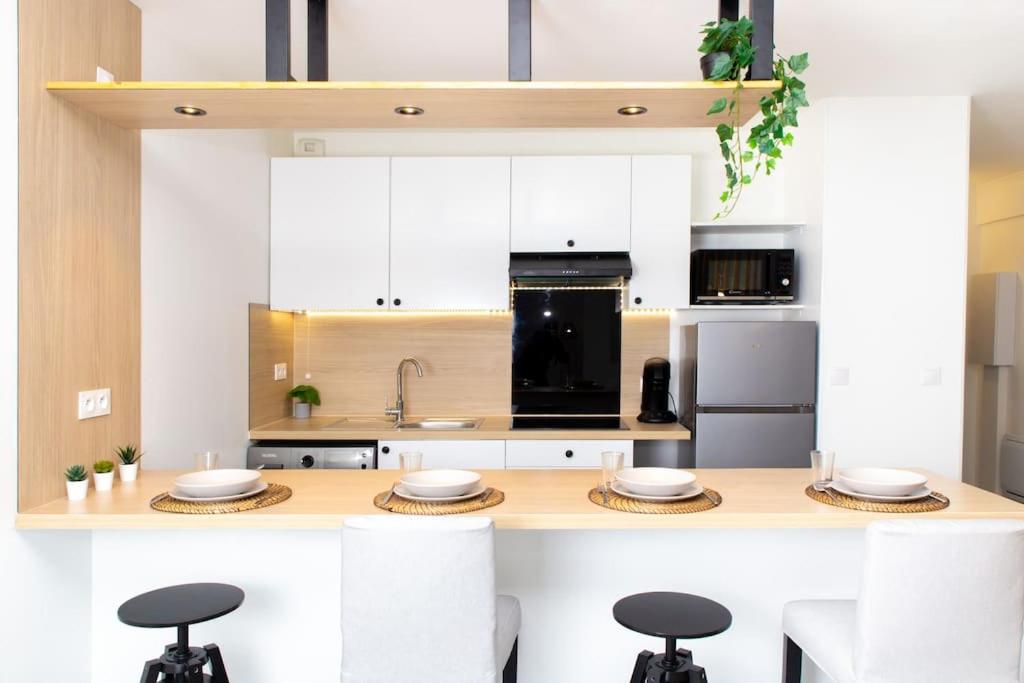 une cuisine avec des armoires blanches et un comptoir avec des tabourets dans l'établissement Appartement Moderne et Tropical 15 min Paris, à Juvisy-sur-Orge