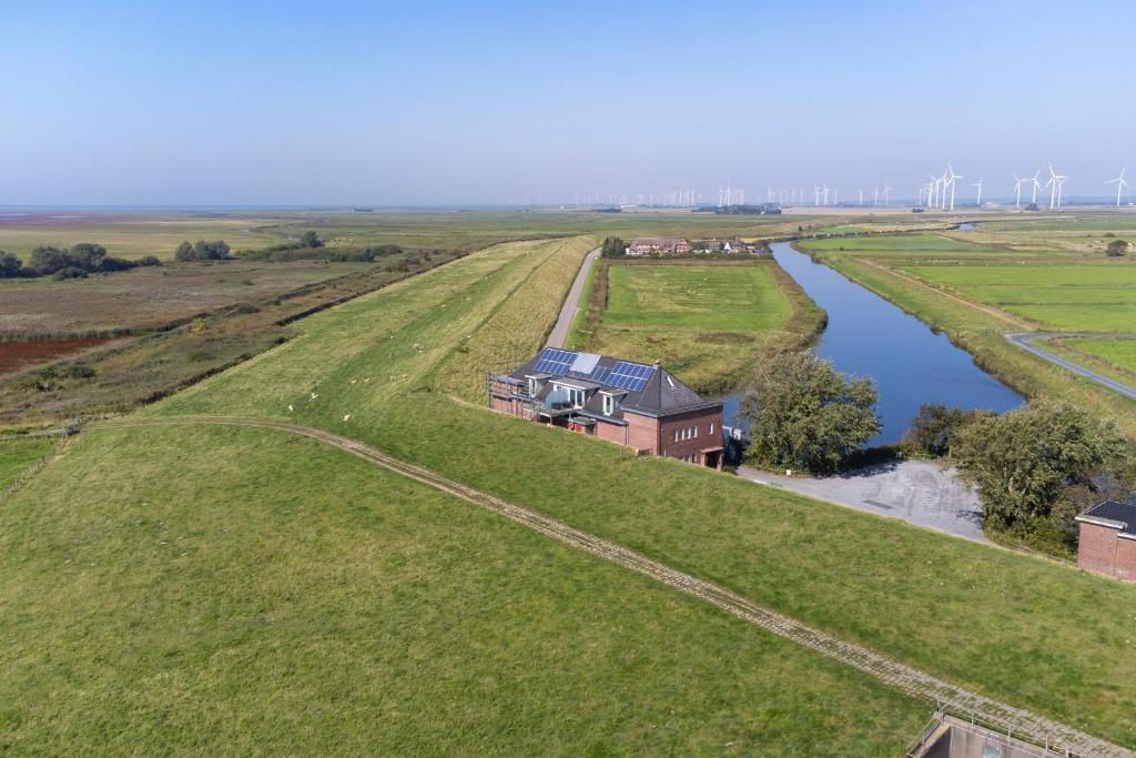an aerial view of a house on a field next to a river at Arlau Schleuse - Schleuse twee in Hattstedtermarsch