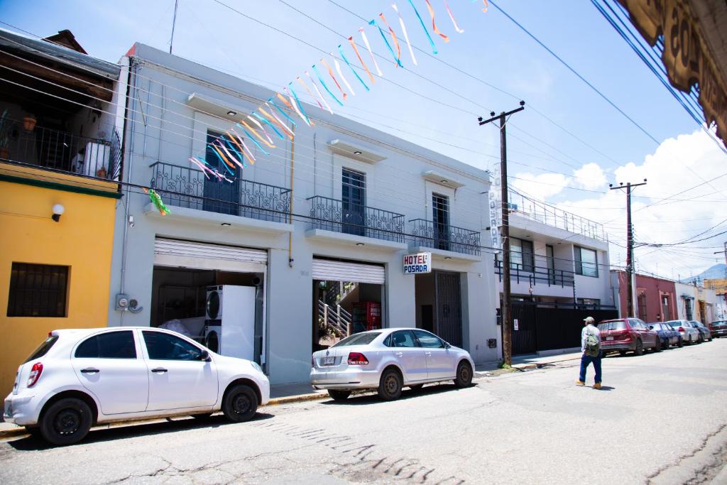 deux voitures garées dans une rue en face d'un bâtiment dans l'établissement Marqués Oaxaca - Hotel, à Oaxaca