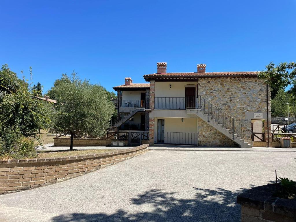 une maison avec un mur en pierre et une allée dans l'établissement Saturnia House, à Poggio Murella