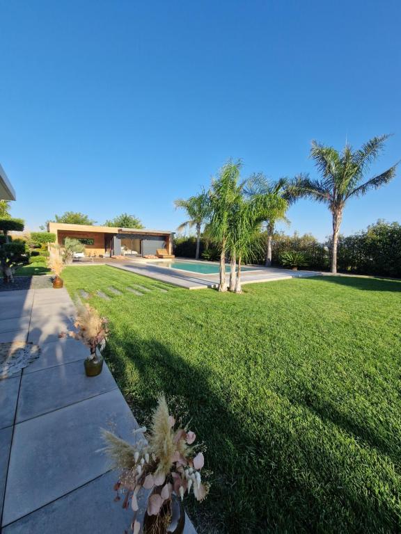 a house with a lawn with palm trees and a sidewalk at The Pool house in La Farlède
