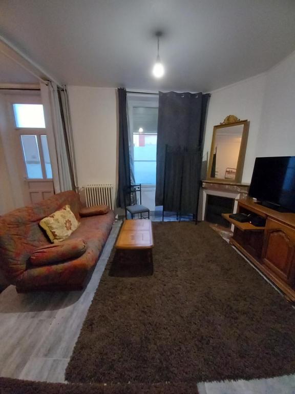 een woonkamer met een bank en een televisie bij Fleurs de lotus 1 in Romilly-sur-Seine