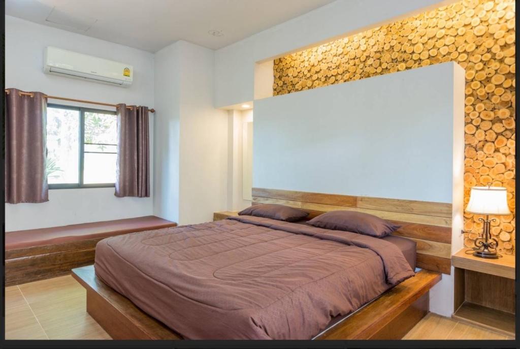 Ban Nong Pa Kha的住宿－บ้านสวนภูรจิตร Baansuanphurajit，一间卧室配有一张大床和木制床头板