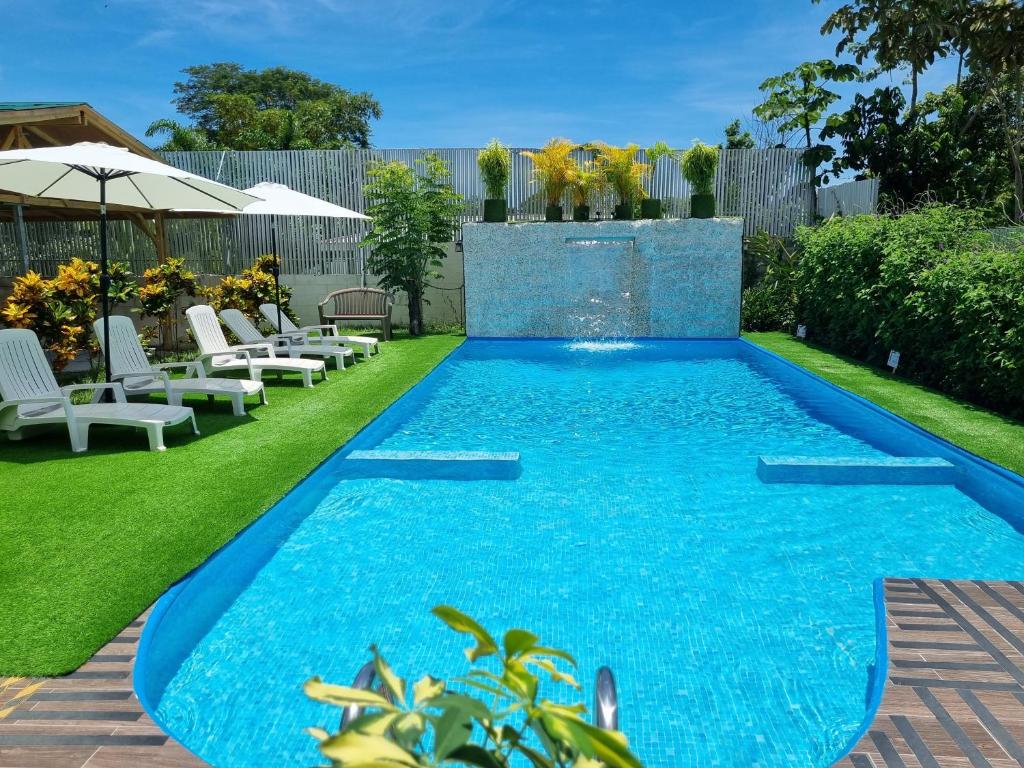 a swimming pool in the middle of a yard with white chairs at Ballena Rey Hotel in Uvita