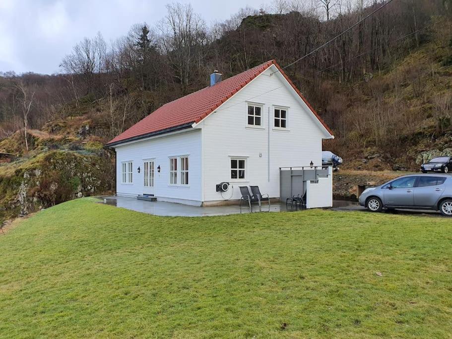 uma casa branca com um carro estacionado num quintal em Moderne hus med 5 soverom og 2 bad på Hidra em Hidra