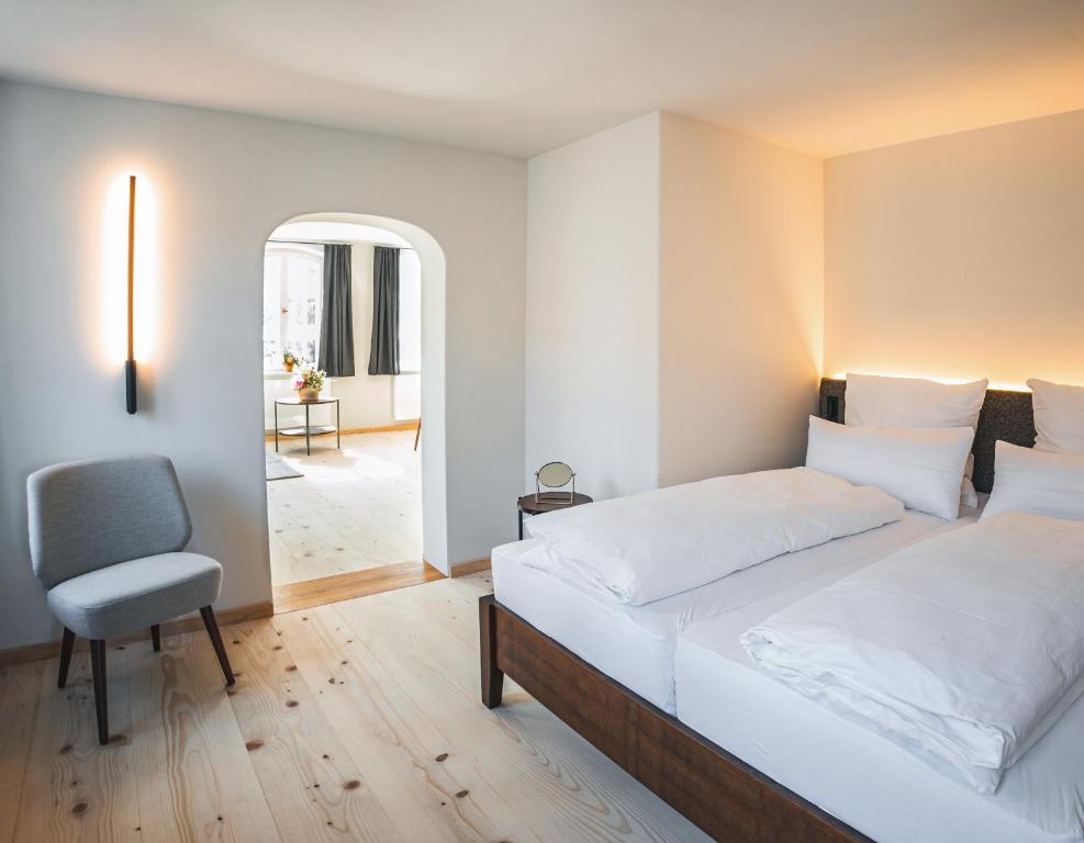 ein Schlafzimmer mit einem großen Bett und einem Stuhl in der Unterkunft Gasthof Zantl in Bad Tölz