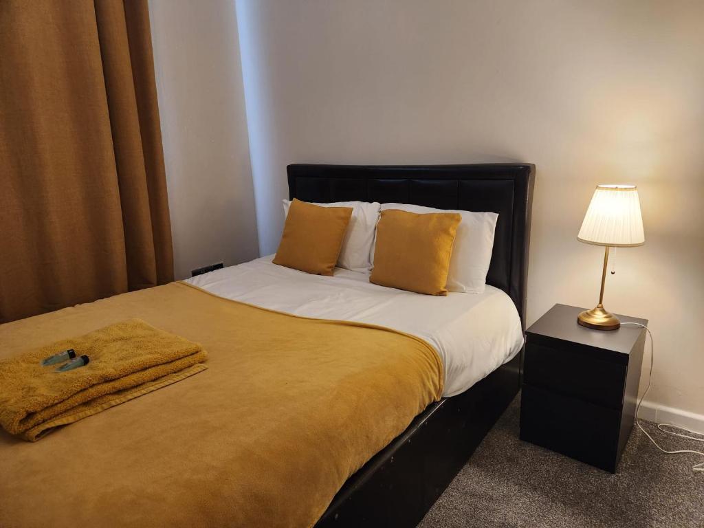 a bedroom with a bed with yellow pillows and a lamp at Home away from Home in Woolwich