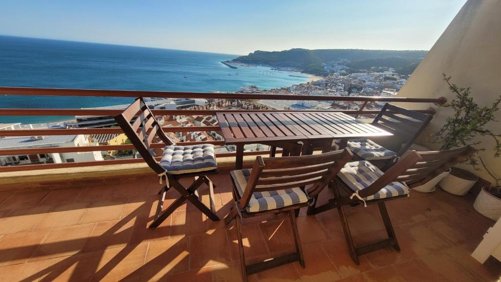 balcón con mesa, sillas y vistas al océano en Casa Amarela _ Sesimbra, en Sesimbra