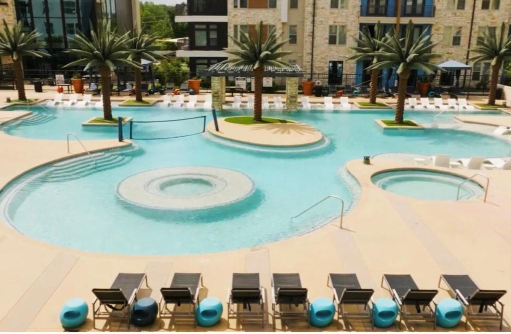 a large swimming pool with chairs and palm trees at 1 BR w Balcony View Resort Pool Free Parking in Addison