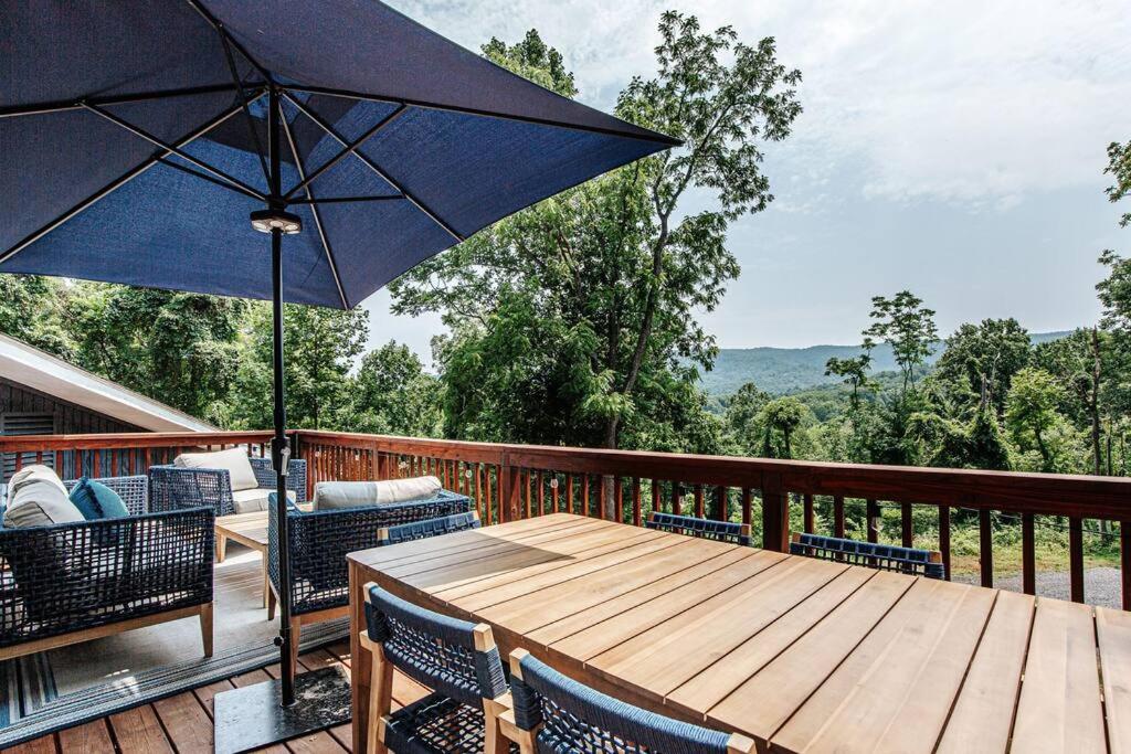 une table en bois avec des chaises et un parasol sur une terrasse dans l'établissement Harmony Ridge Hideaway: mountain retreat w/hot tub, à Front Royal
