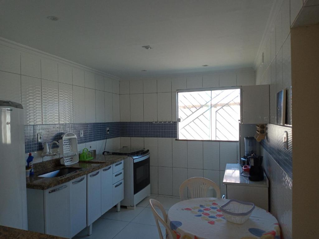 uma cozinha com uma mesa, um lavatório e uma janela em Casa jauá em Camaçari