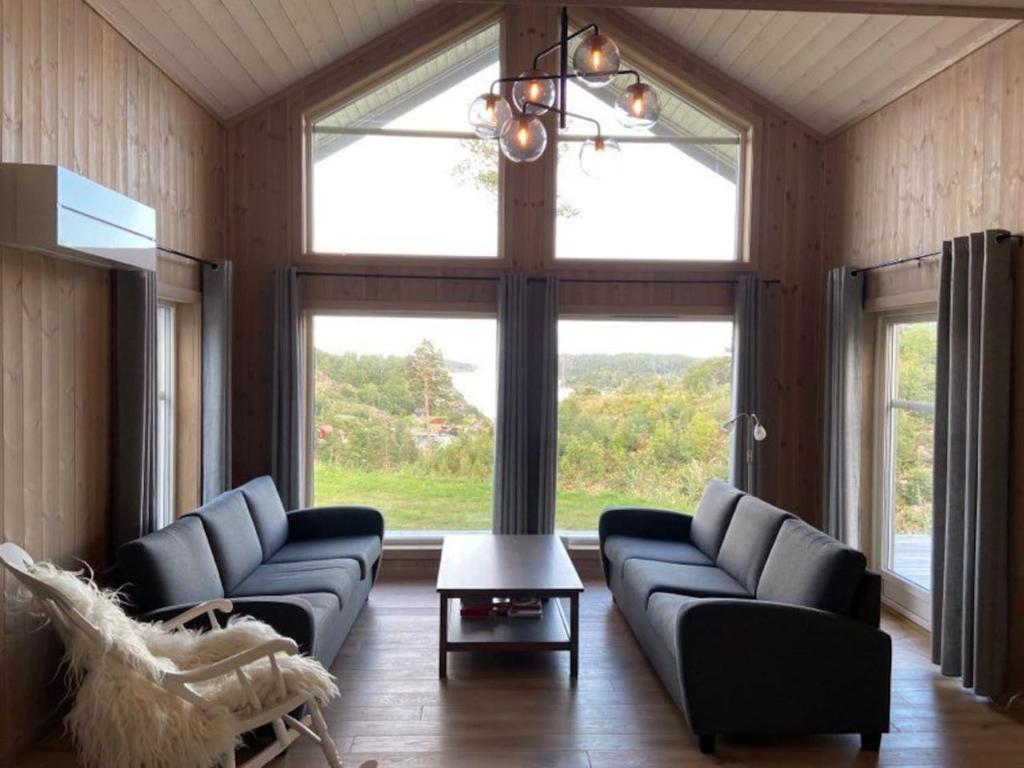 a living room with two couches and a large window at Flott nyere hytte med sjøutsikt. in Risør