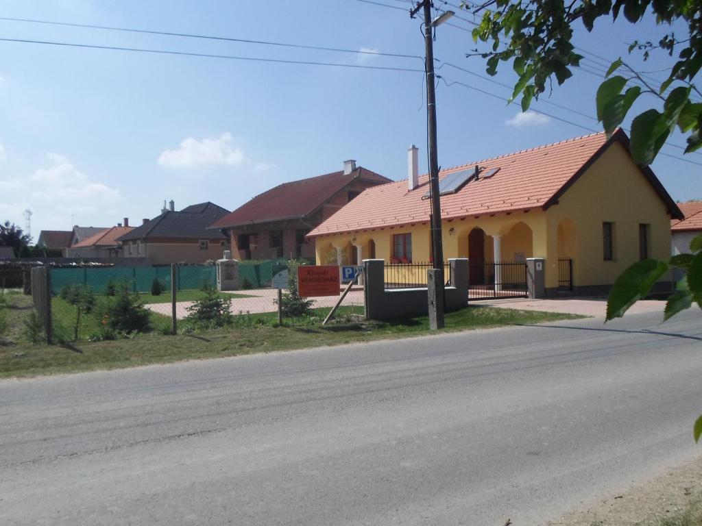 uma casa amarela com um telhado vermelho numa rua em Kiserdő Vendégház em Rajka