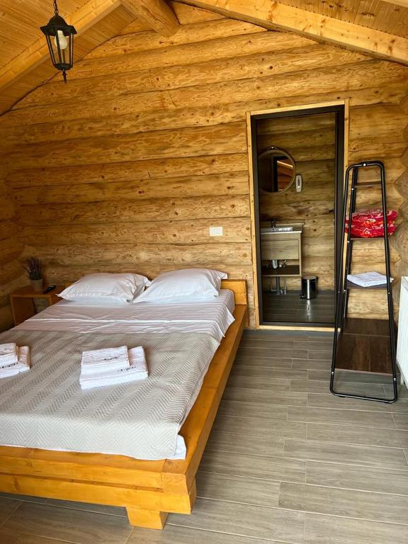 una camera da letto con un letto in una cabina di legno di M&V Infinit a Sălătrucel
