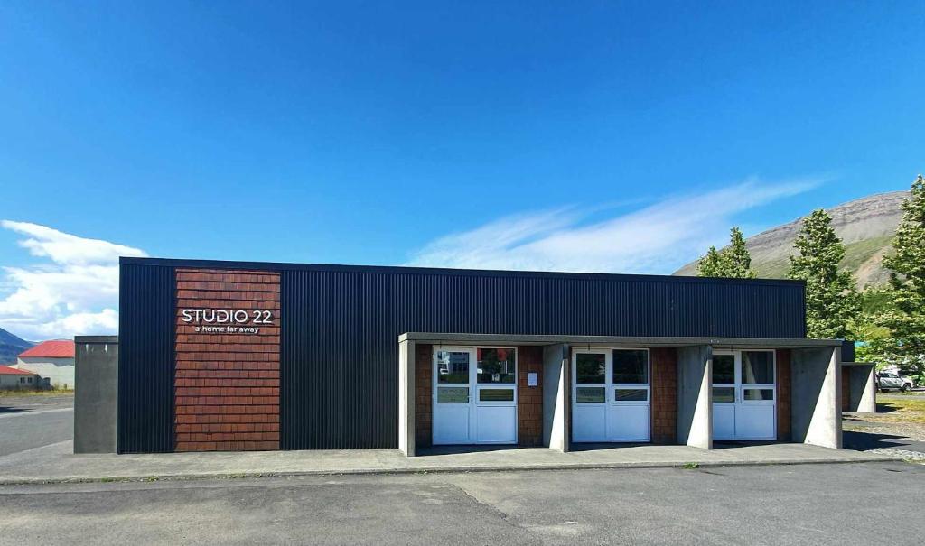 budynek z dwoma białymi drzwiami na parkingu w obiekcie Studio 22 w mieście Reyðarfjörður