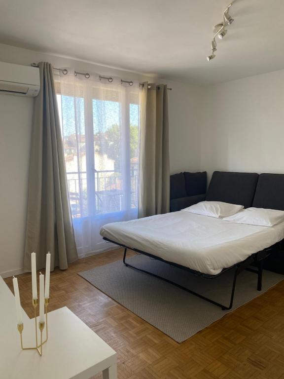 a bedroom with a bed and a couch and a window at Petit cocon avec Balcon au centre de Marseille in Marseille