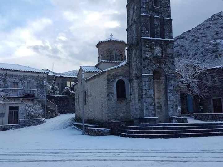 um velho edifício de pedra com uma torre na neve em Mani Milea Mountain Home em Miléa