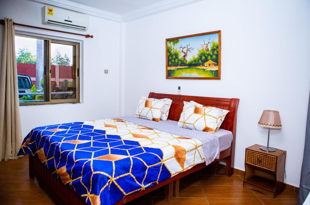 a bedroom with a bed with a blue and white comforter at Luxor garden apartments Accra Ghana in Accra