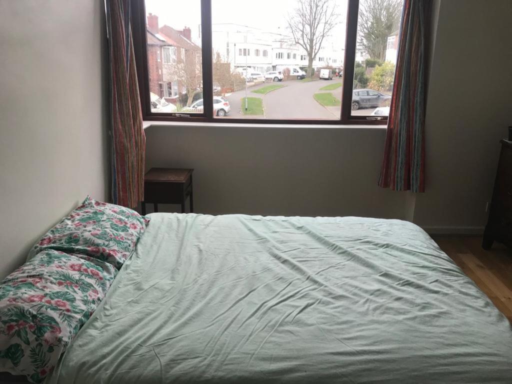Large Room in share house في Meanwood: سرير في غرفة نوم مع نافذة كبيرة