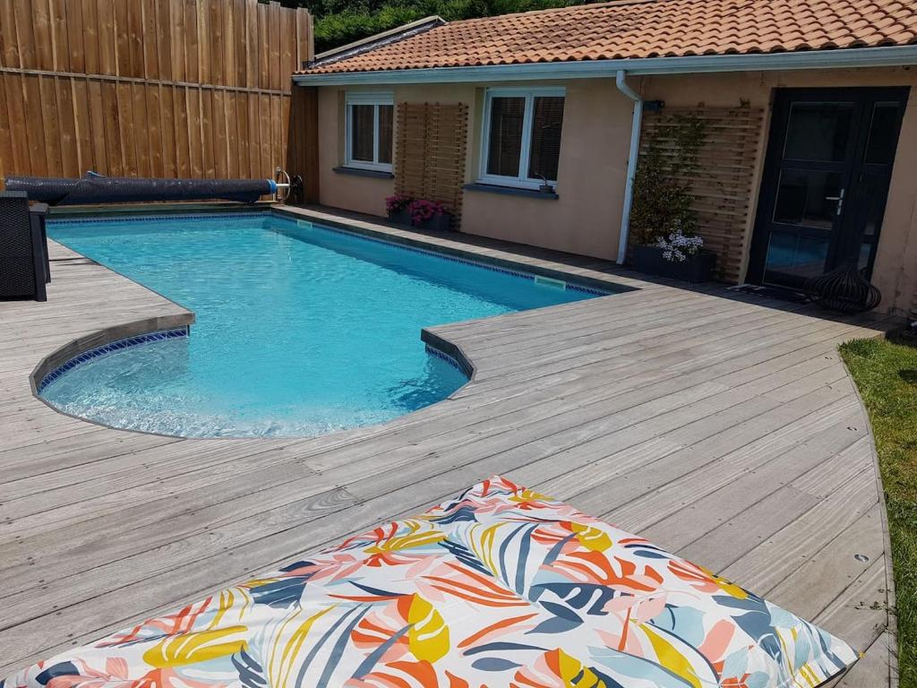 uma piscina com um deque de madeira ao lado de uma casa em Jolie Dépendance em Le Brucat