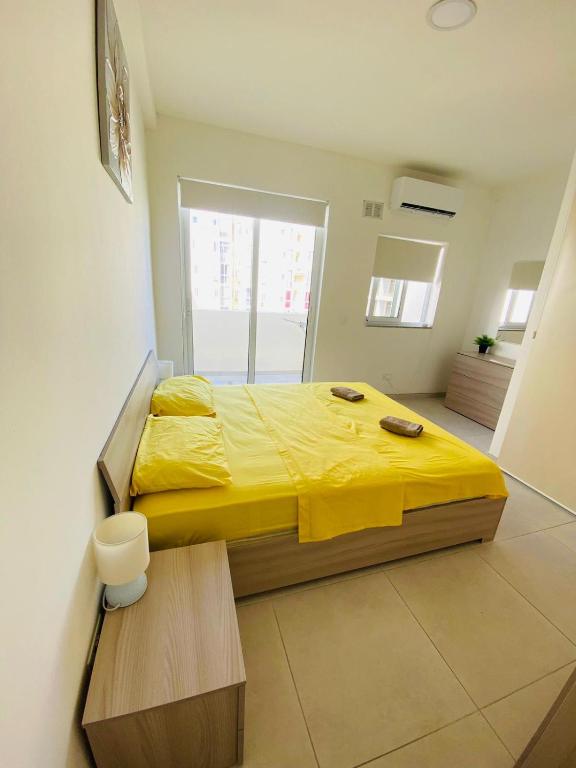 una camera da letto con un letto e un piumone giallo di Amnesia Apartment a San Pawl il-Baħar