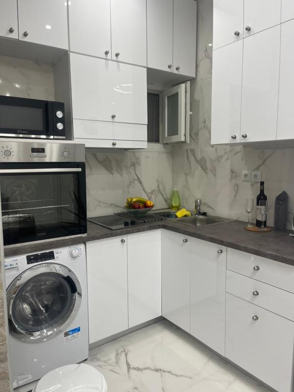 una cucina bianca con lavatrice e forno a microonde di White Apartment Athens ad Atene