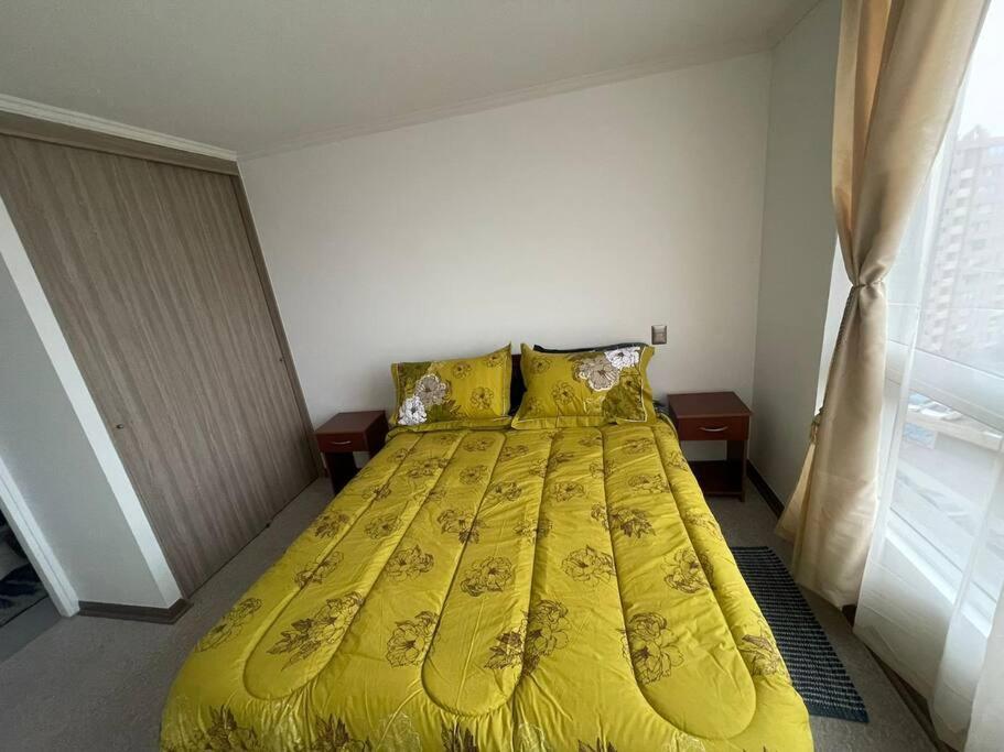 Ce lit se trouve dans une chambre dotée d'un couvre-lit jaune. dans l'établissement Excelente Departamento 2 habitaciones 2 baños Iquique, à Iquique